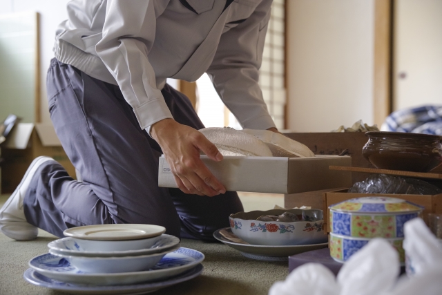 和室で食器を箱詰めする人の様子